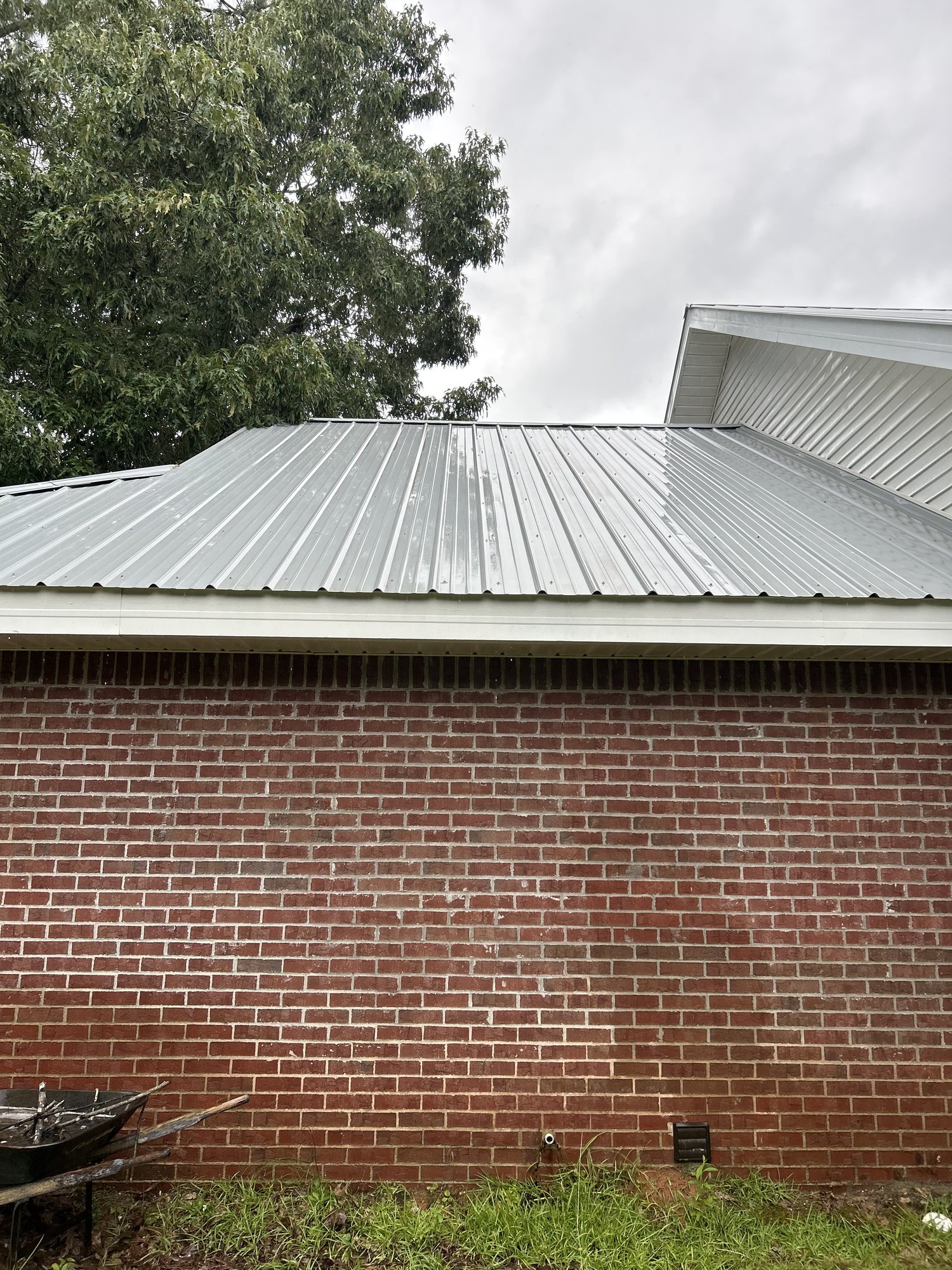 Clean metal roof meeting the brick wall of the home, finished job.
